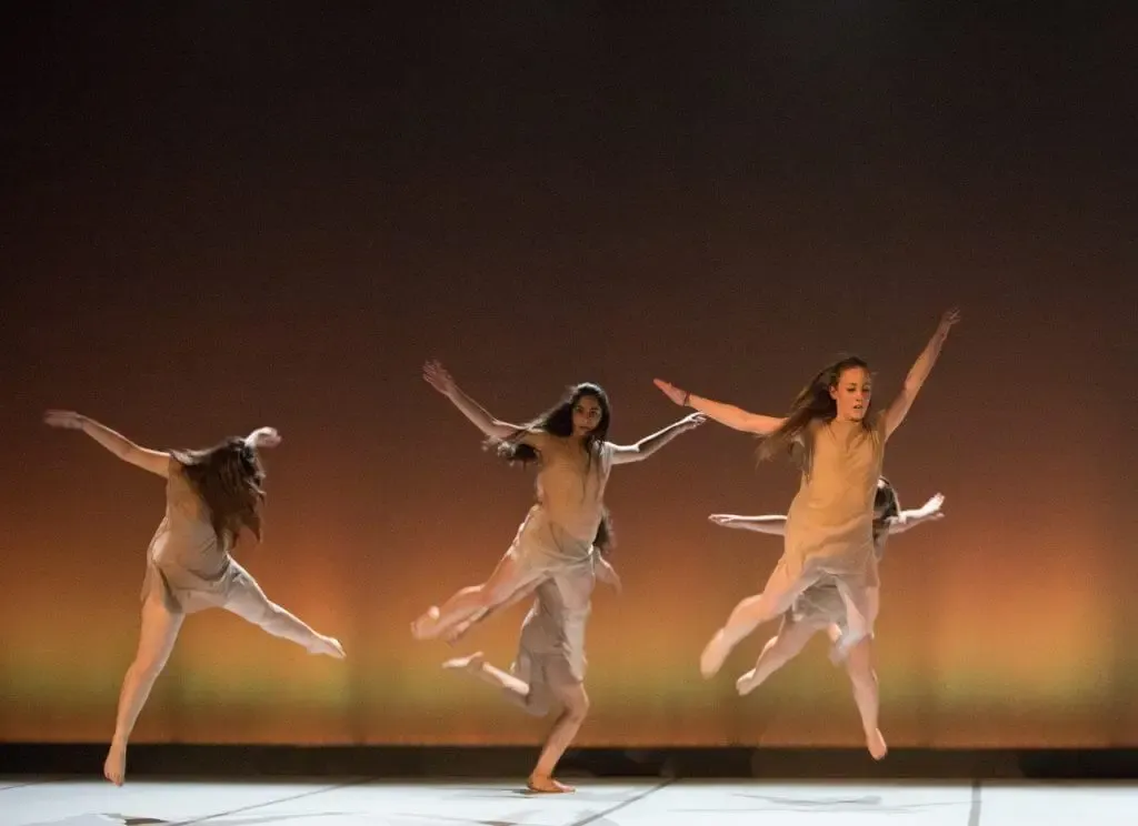 Tre danzatrici di danza contemporanea in salto sul palco